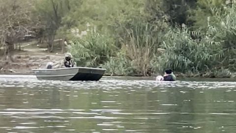 A screen grab from a video obtained by CNN shows a woman holding a crying baby in her arms in the Rio Grande yelling for help, as members of the Texas National Guard watch from nearby boats, but do not intervene.